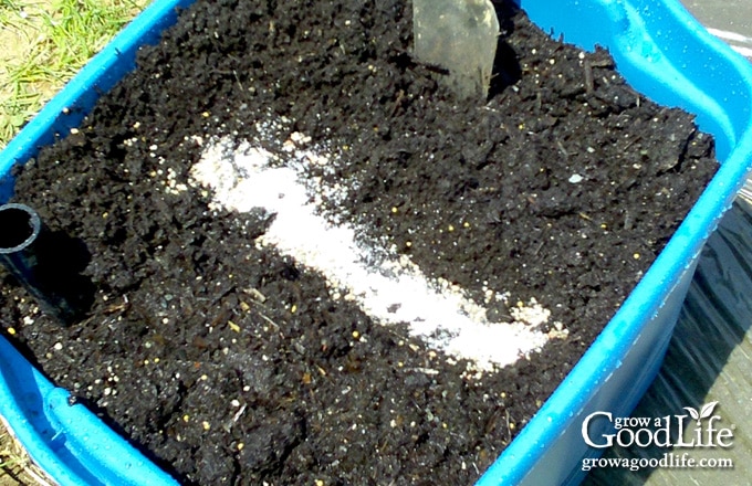 Granular fertilizer placed in a shallow trench across the top of a self-watering planter.