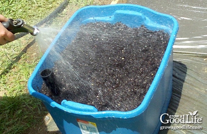 Layering damp potting mix into an 18-gallon self-watering planter.