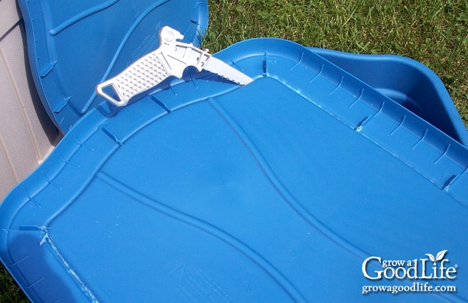 Cutting the center out of a storage tote lid to create the aeration shelf for a self-watering planter.