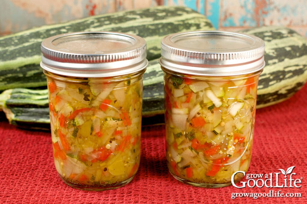 Two pint jars of home canned sweet zucchini relish on a red towel.