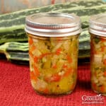 Two jars of home canned zucchini relish on a table.