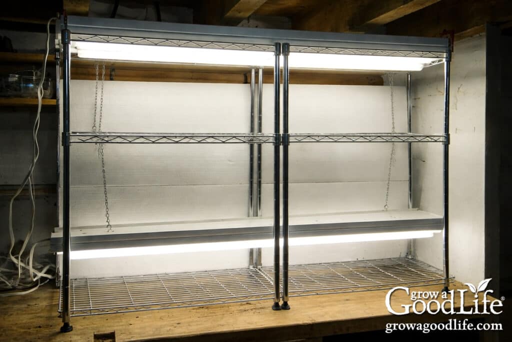 Empty DIY grow light shelving unit with hanging lights set up on a workbench before adding seed trays.