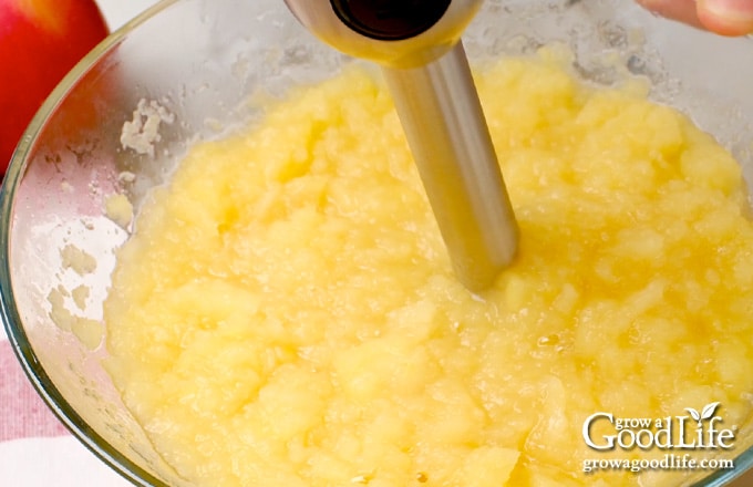 Pureeing the cooked apples with a handheld stick blender.