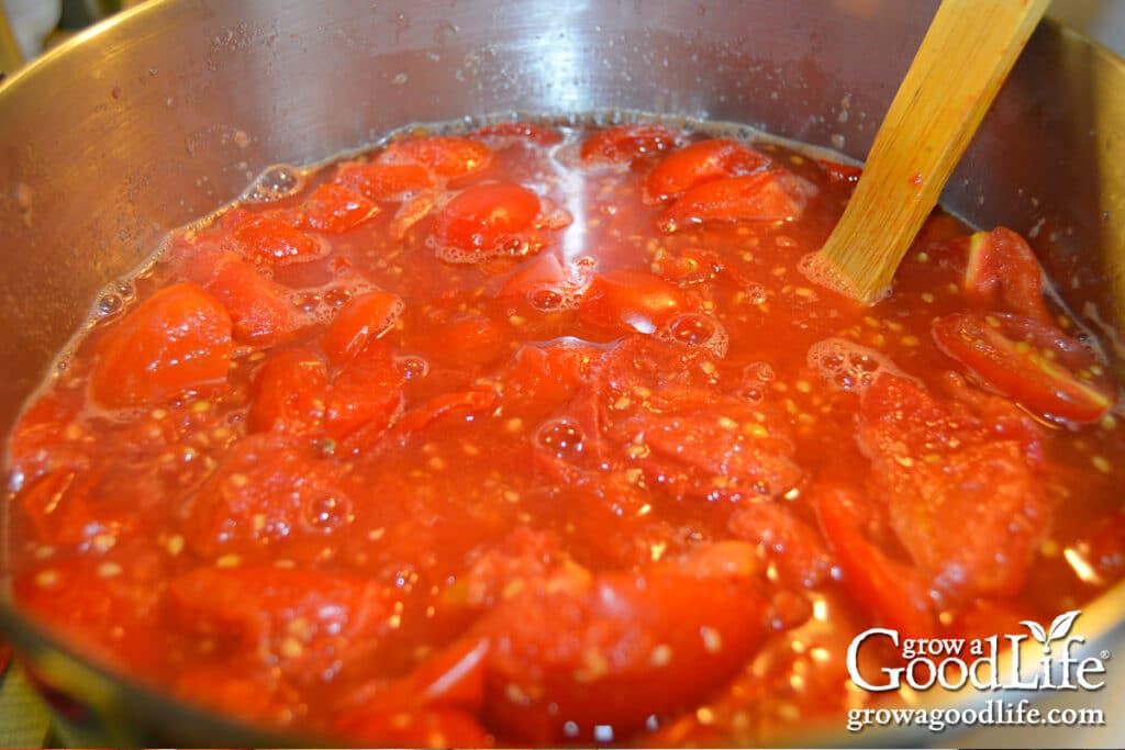 Overhead view of tomatoes cooking down in a pot, reducing into thick seasoned tomato sauce.