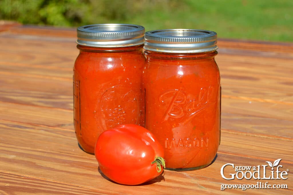 Two pint jars of home canned seasoned tomato sauce on a wooden table, ready for storage.