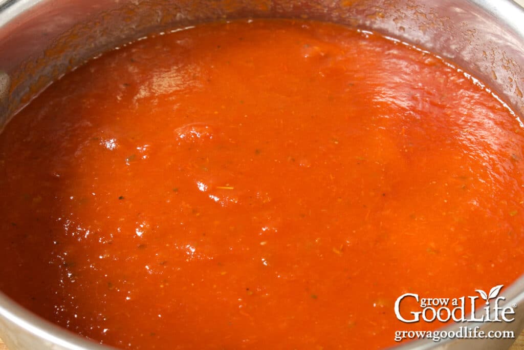Overhead view of smooth seasoned tomato sauce simmering in a pot on the stove, ready for canning.