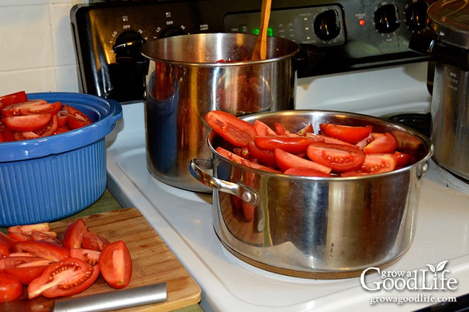 two pots of tomatoes on the stove for tomato sauce