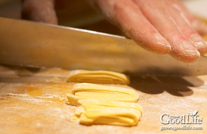 close up image of a knife cutting dough into noodles