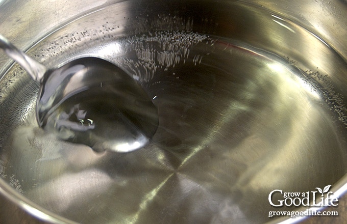 Overhead view of vinegar warming in a saucepan for wild violet vinegar infusion.