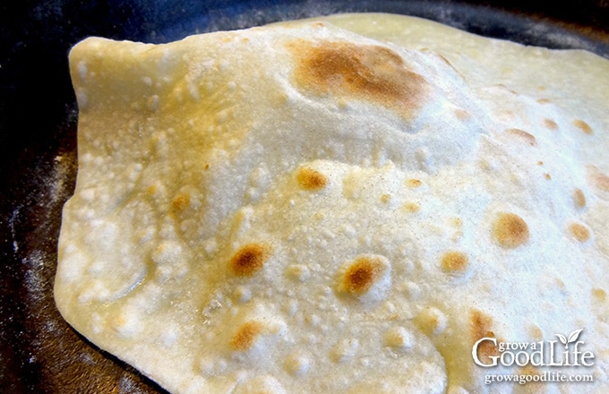 flour tortilla cooking in a cast iron skillet