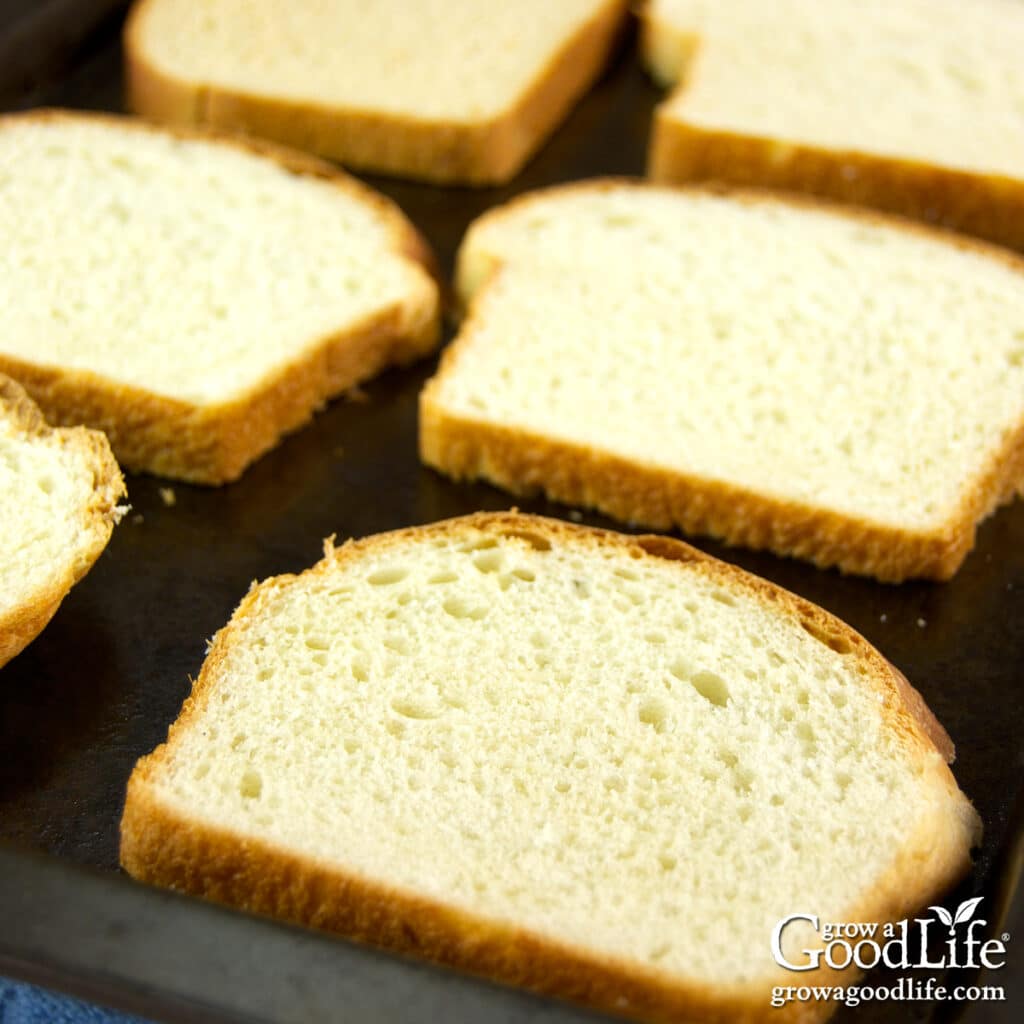 Bread slices spread on a baking sheet air drying for homemade bread crumbs.