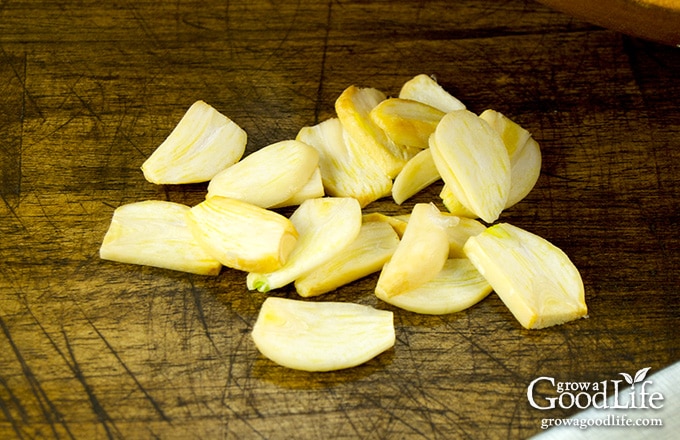sliced garlic on a dark brown cutting board