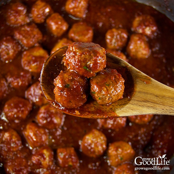 closeup of three meatballs on a wooden spoon