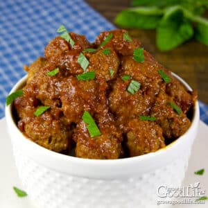 A white bowl filled with homemade barbecue meatballs coated in smoky BBQ sauce on a table.