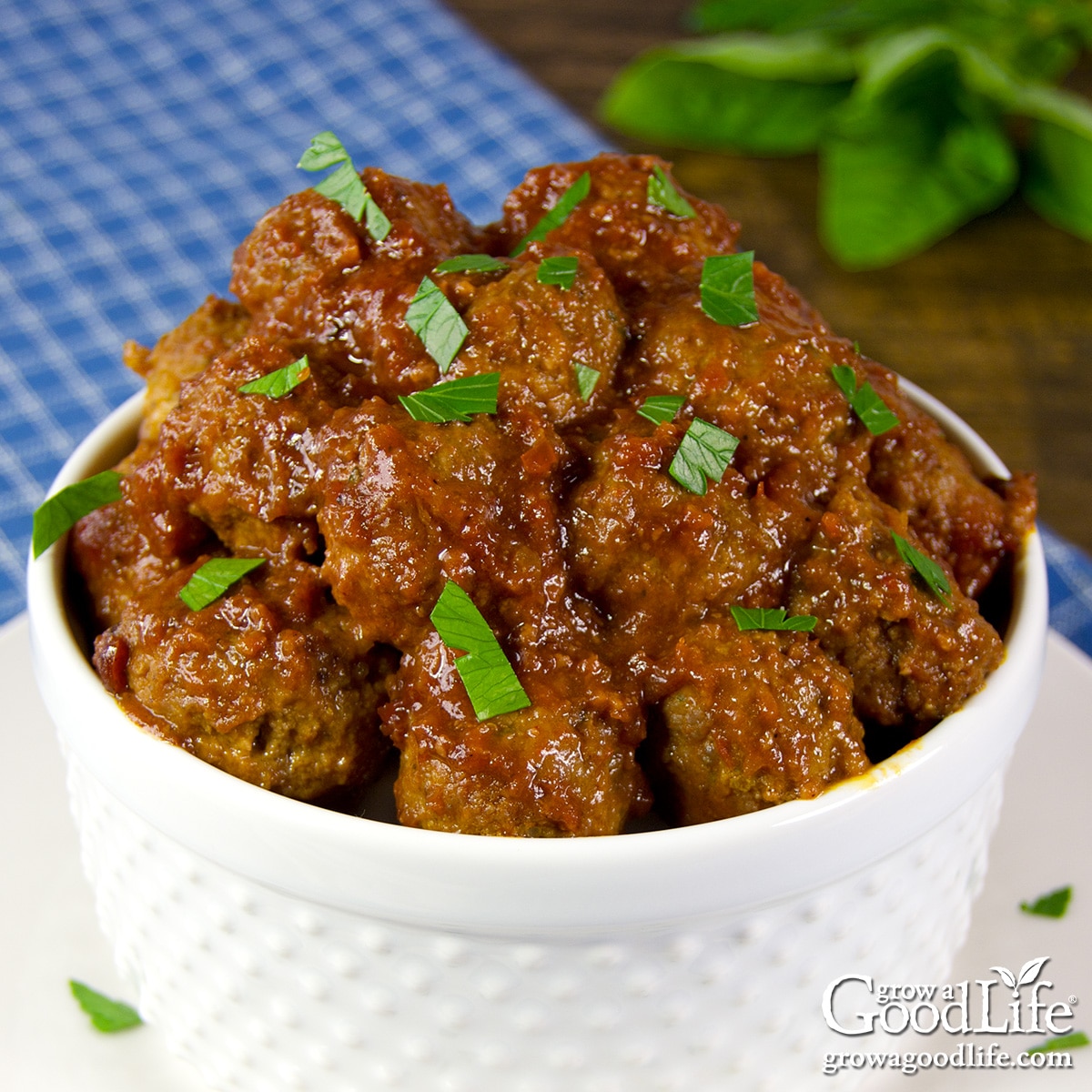 A white bowl filled with homemade barbecue meatballs coated in smoky BBQ sauce on a table.