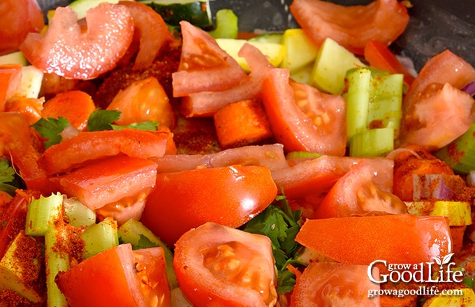 closeup of tomatoes, celery, peppers, onions, and parsley in a saucpot