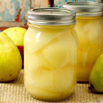 fresh pears and jars of canned pears on a table