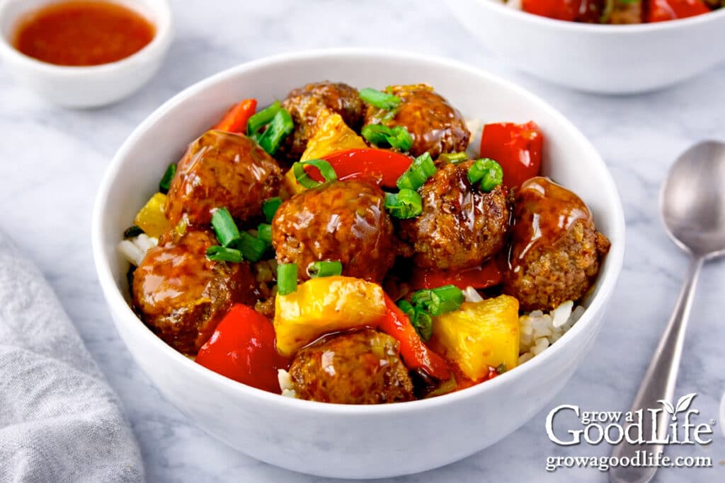 Sweet and sour meatballs served over rice with pineapple and red bell peppers.