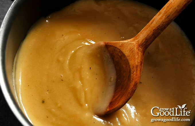 overhead photo of turkey gravy in a pot with a wooden spoon