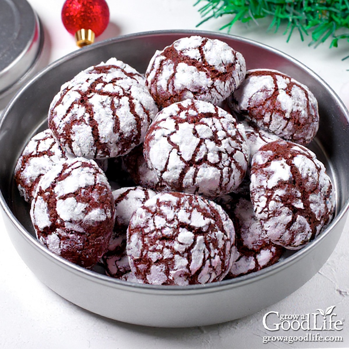 A silver cookie tin filled with homemade chocolate crinkle cookies.
