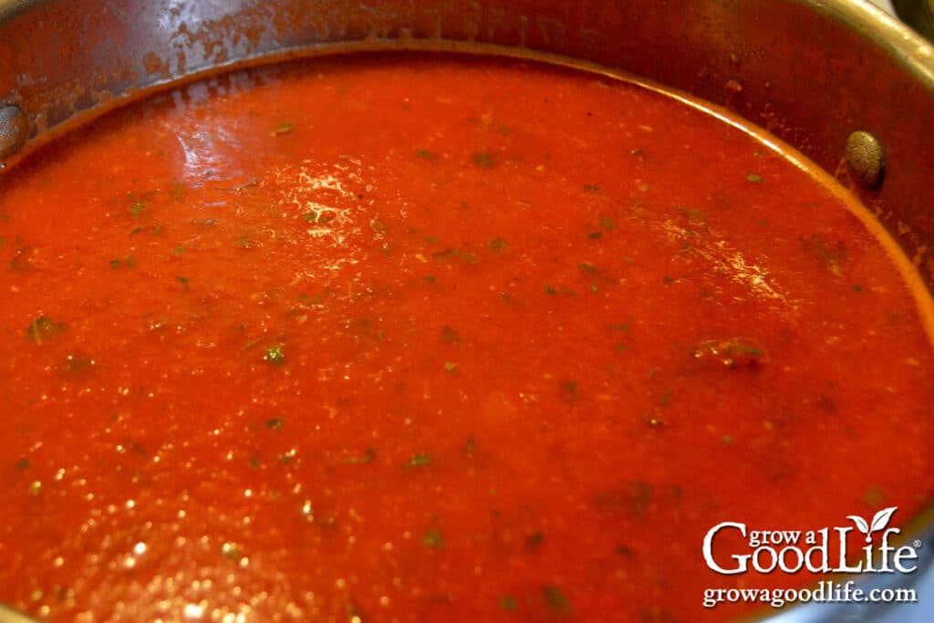 Overhead view of thick pizza sauce simmering in a large pot on the stove.