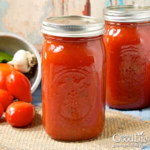 Two quart jars of homemade spaghetti sauce preserved with pressure canning on a table.