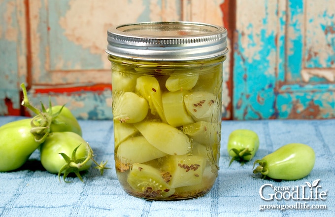 a jar of pickled green tomatoes on a table