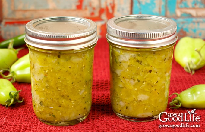 Jars of home canned green tomato salsa on a table.