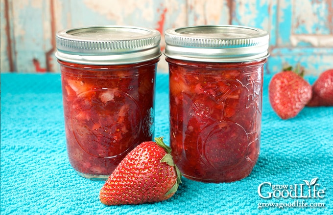 Jars of home canned strawberry jam on a table.