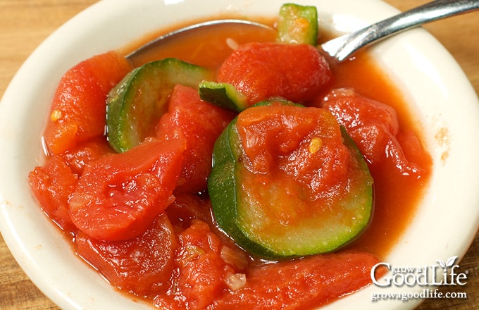 Over head of a bowl of stewed tomatoes and zucchini.