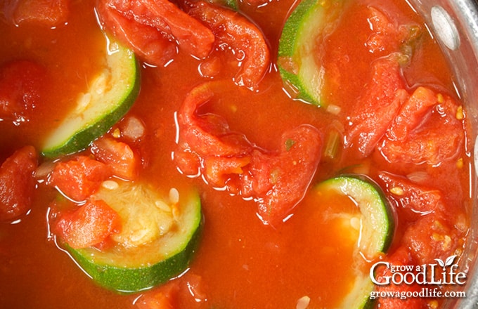 Close up of zucchini and tomatoes simmering in a pot.