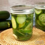 Jars of home canned zucchini pickles on a table.