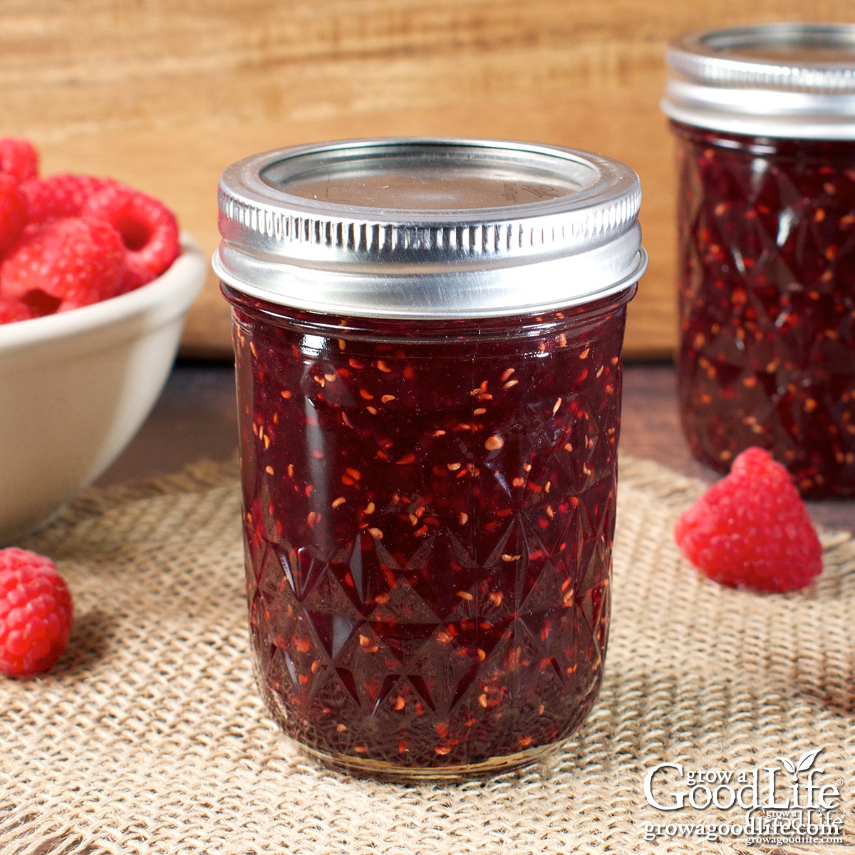 Half-pint jars of low sugar raspberry jam sealed and cooling on a table.
