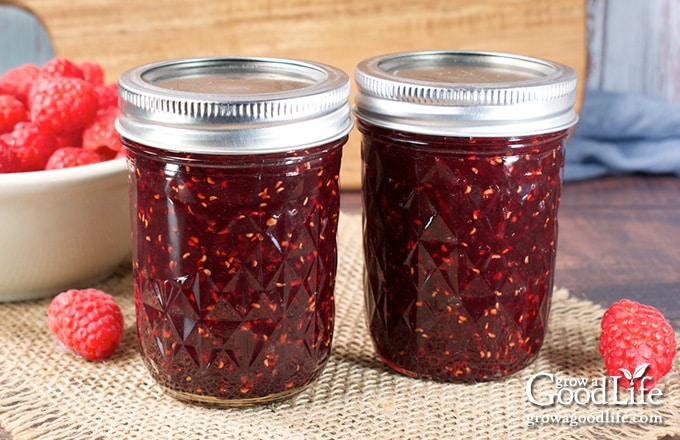 Jars of home-canned strawberry jam on a table.
