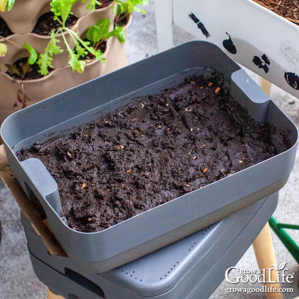 A multi-layered worm composting bin on a patio.