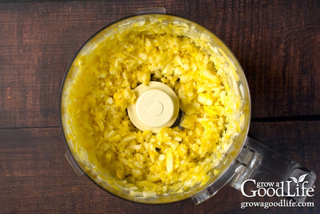 Close up of shredded summer squash in a food processor bowl.