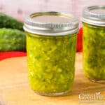 Jars of home canned dill relish on a table.