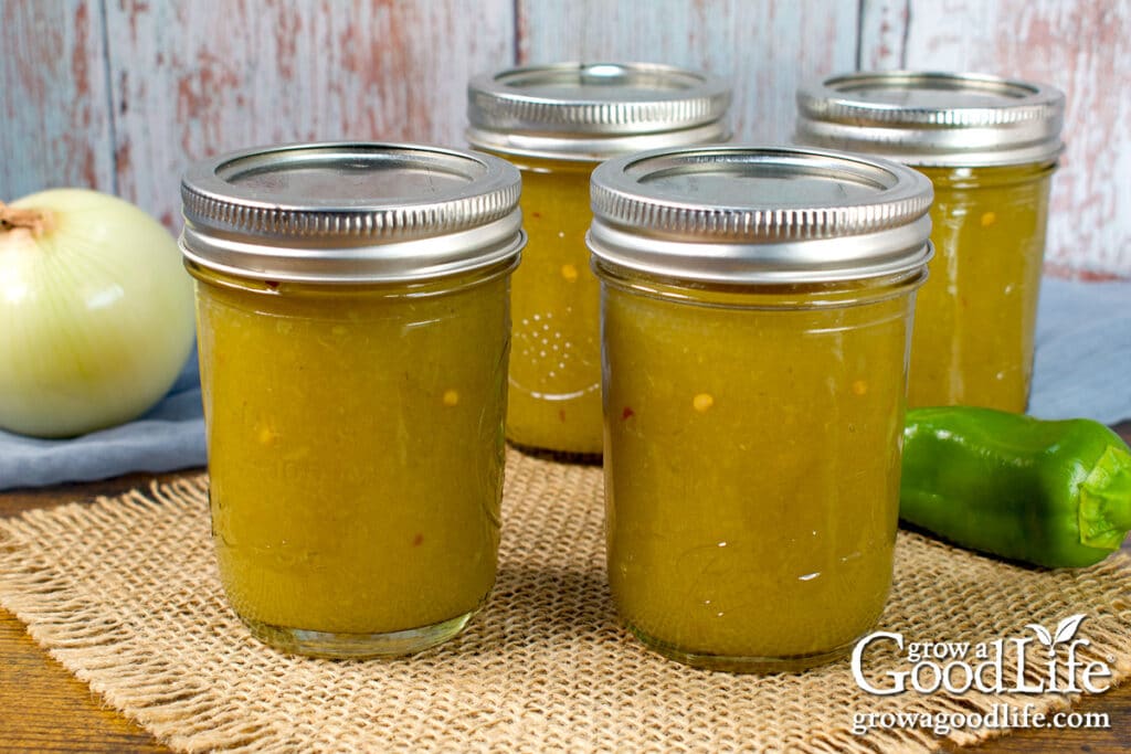 Four jars of home canned green chile enchilada sauce on a table.