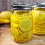 Jars of home canned pickled yellow summer squash on a table.