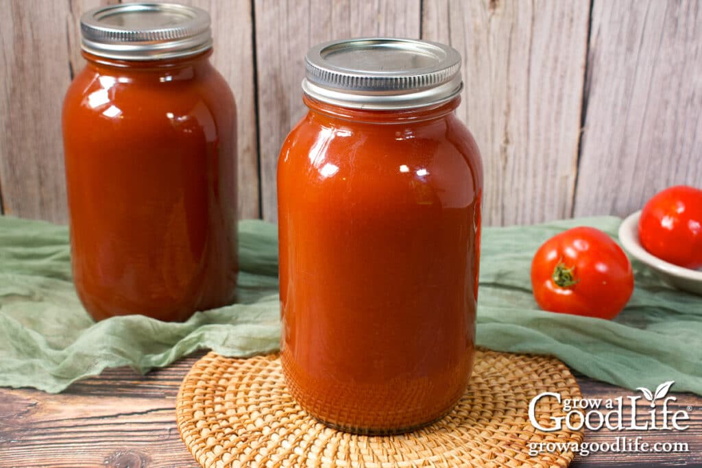 Two quart jars of home canned tomato juice on a table.