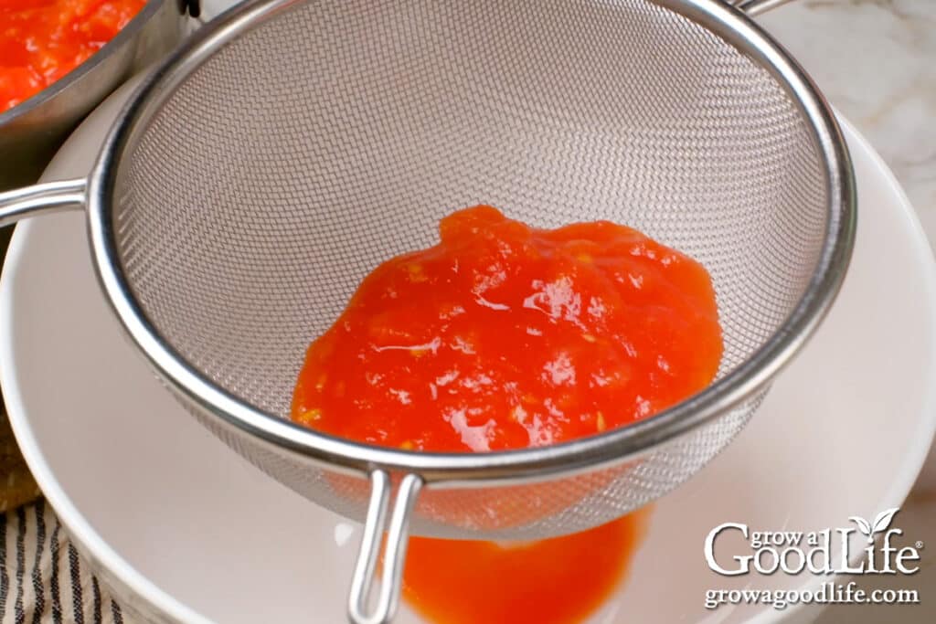 Straining the tomatoes through a fine mesh strainer.