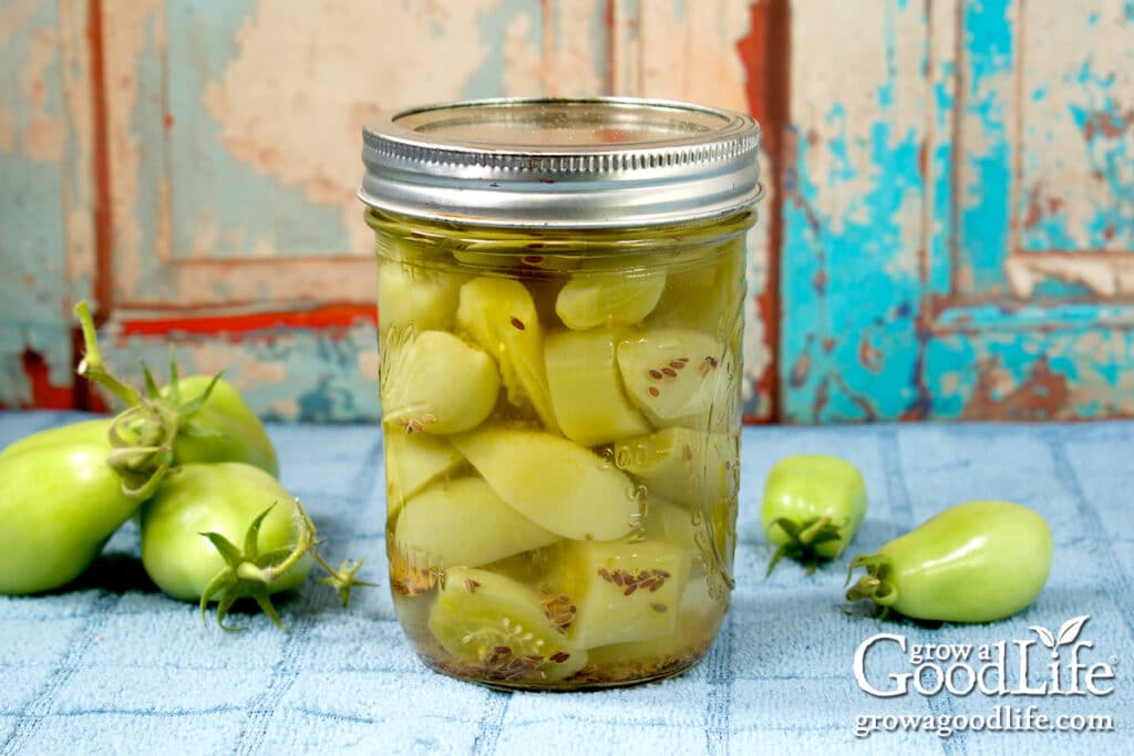 A jar of pickled green tomatoes on a table.