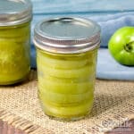 Jars of sliced green tomatoes on a counter.