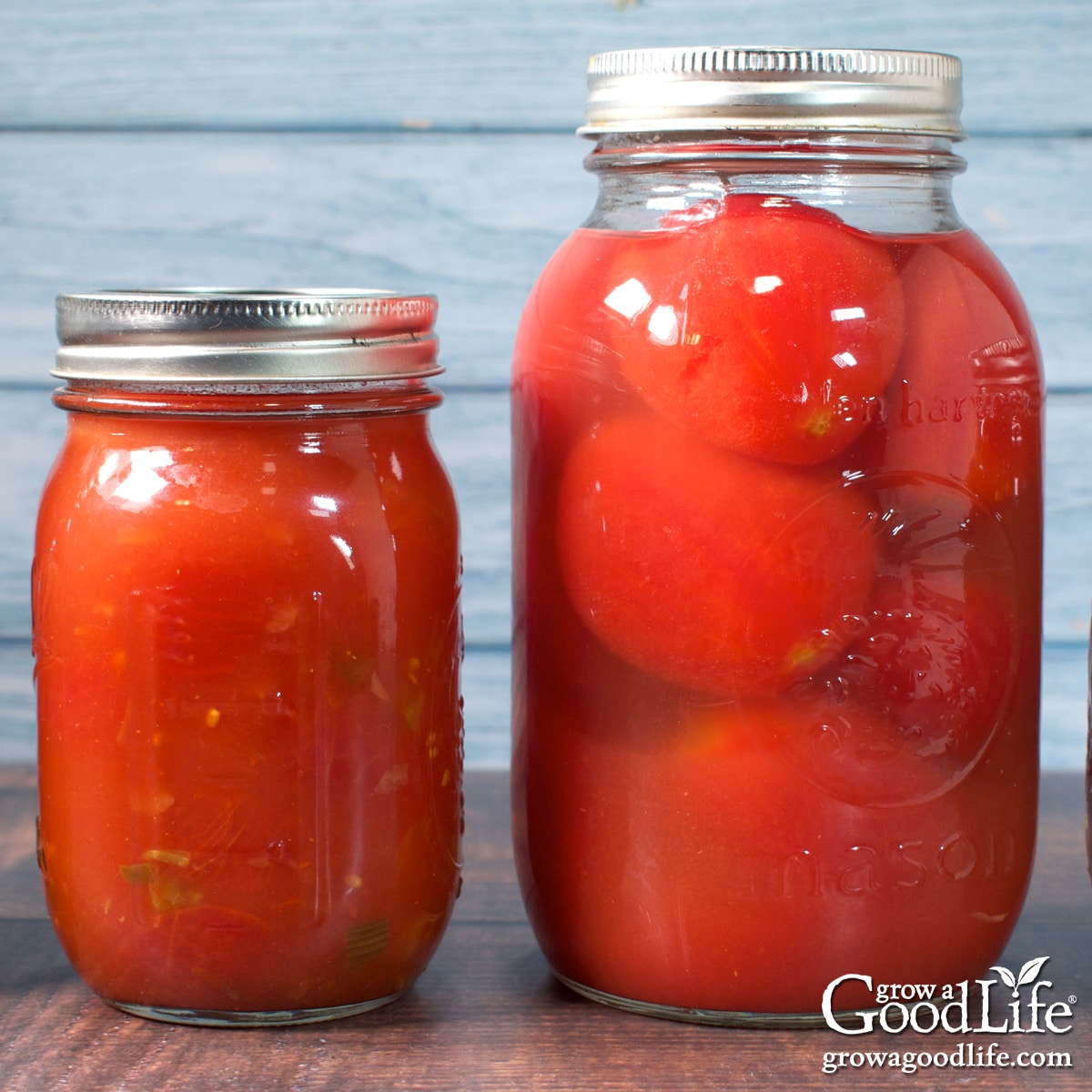 A quart jar of home canned whole tomatoes and s pint jar of stewed tomatoes on a table.