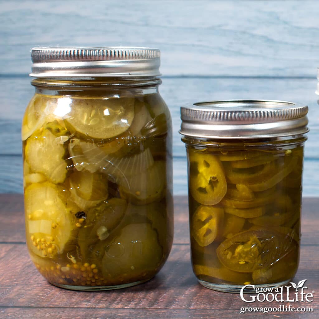 Jars of home canned pickled cucumbers and jalapenos on a table.