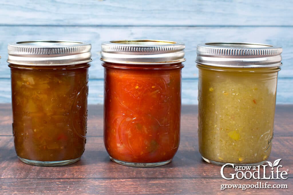 Three half-pint jars of home canned salsa on a counter.