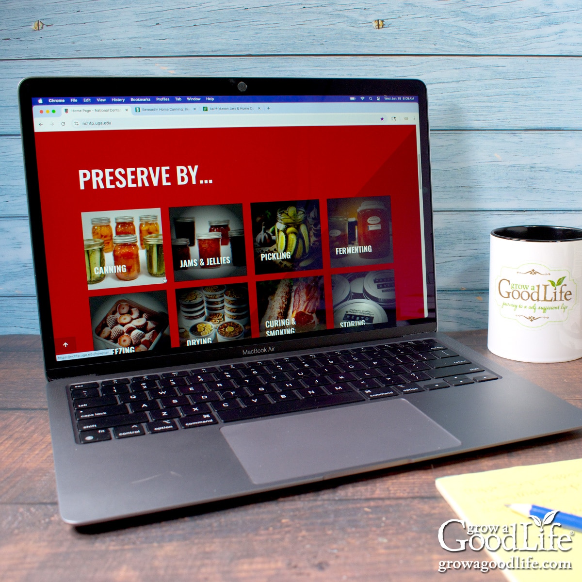 A desk with stacks of canning books and a computer with a canning website on the screen.