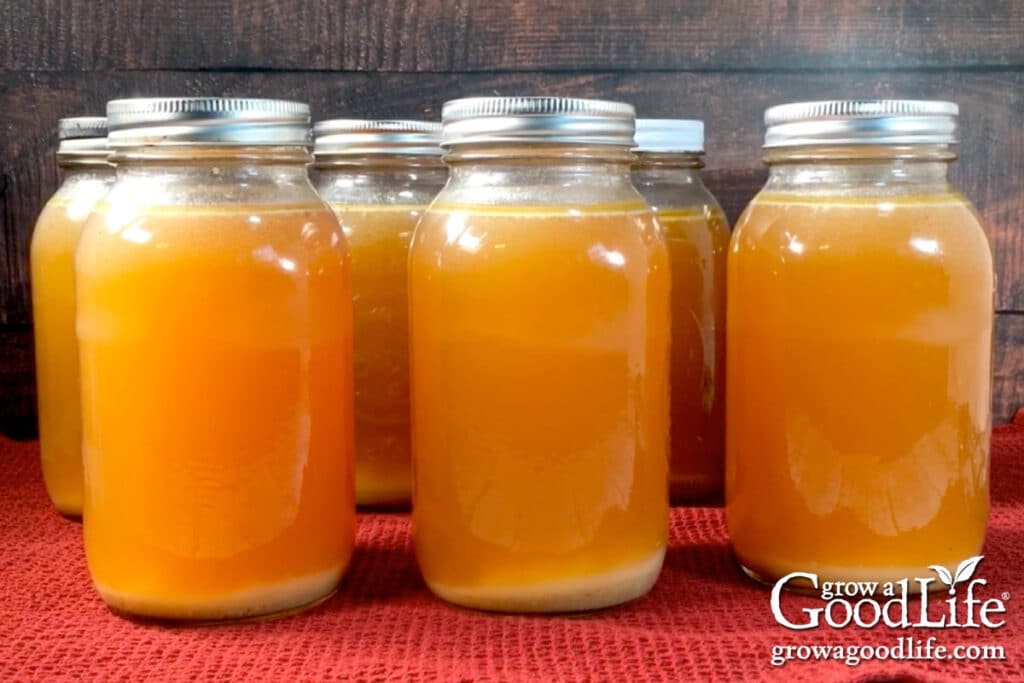 Quart sized jars of pressure canned stock cooling on the counter.