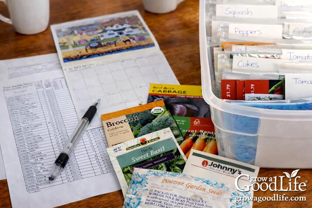 Seed packets, calendar, and a seed starting schedule laid out on a kitchen table.