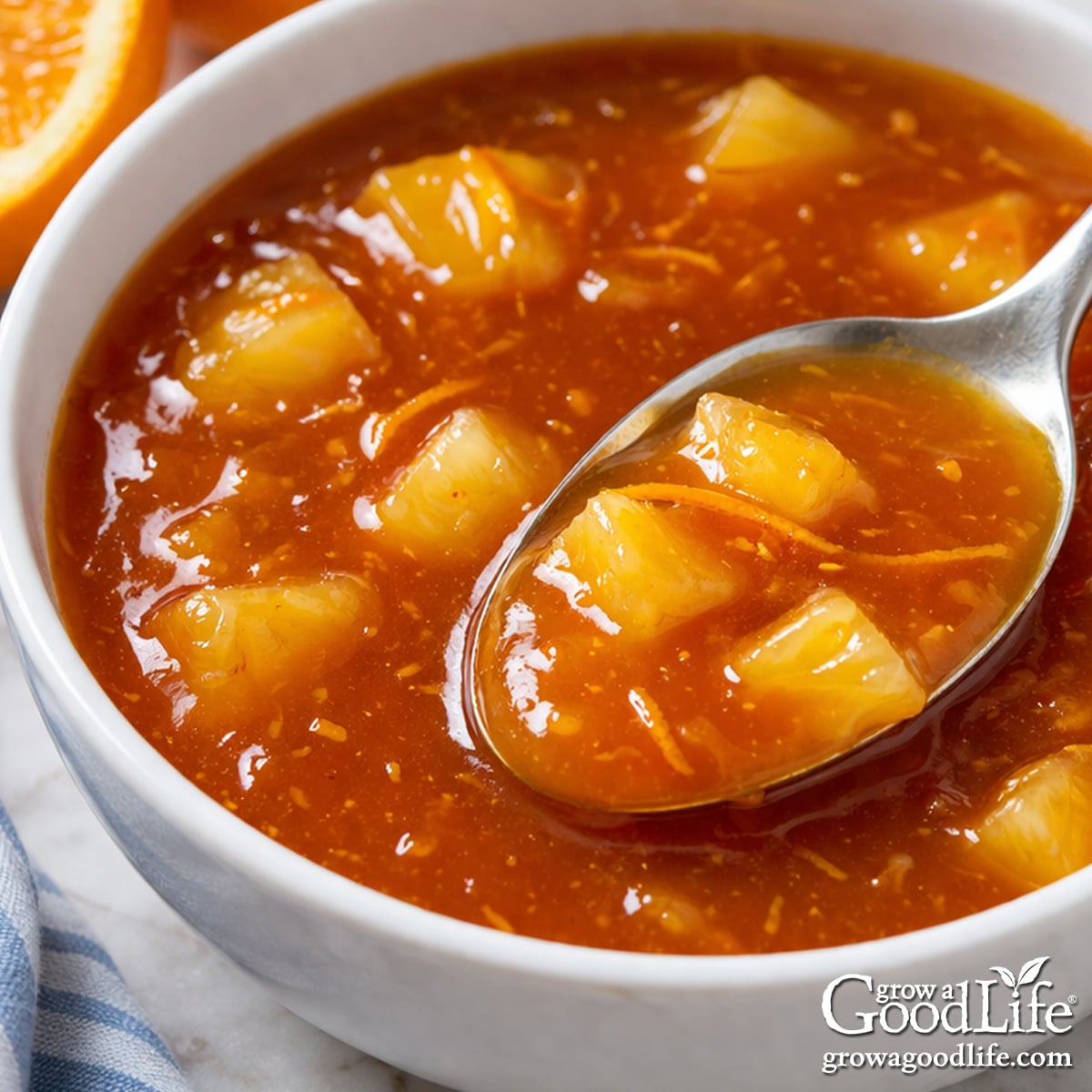 Orange sweet and sour sauce in a bowl with a glossy texture and visible orange zest and pineapple.
